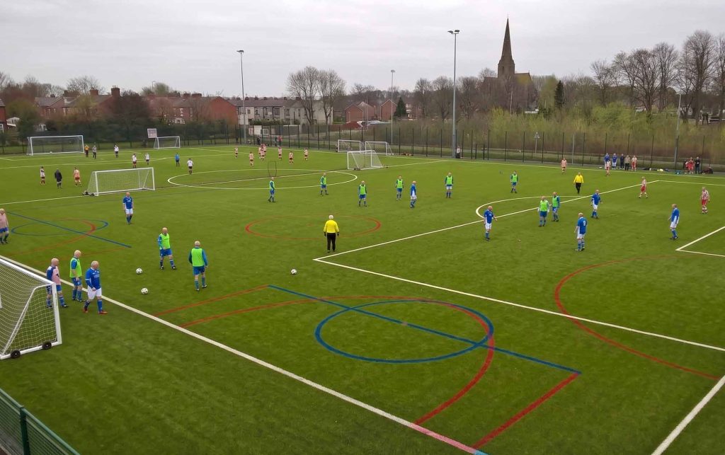 Men playing football on artificial pitch